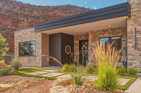 A modern house with a stone facade, large windows, and a landscaped front yard.