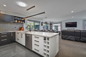 A modern kitchen with a central island, built-in cabinetry, and a dining area with a sofa and a flat-screen TV.
