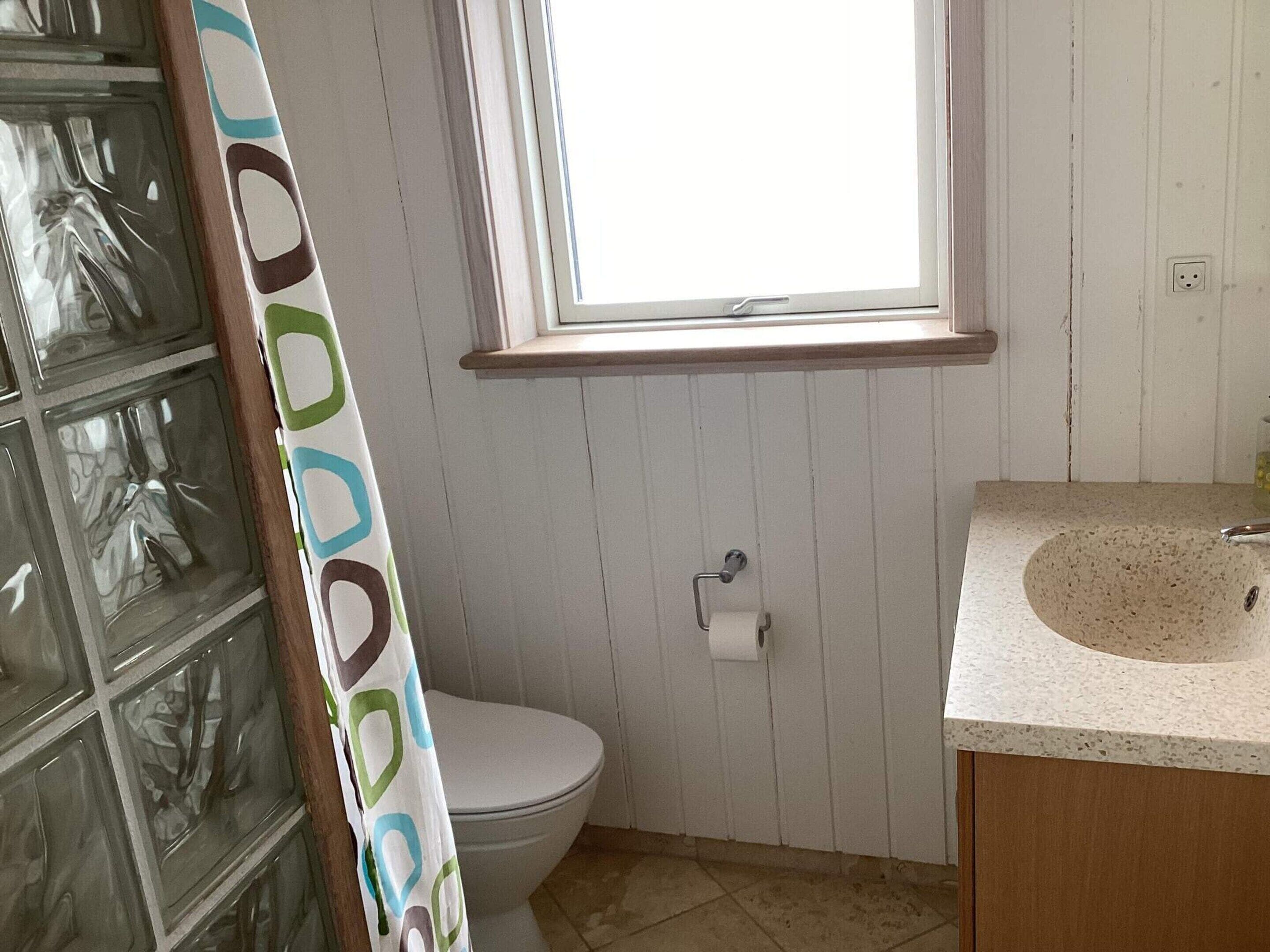 A bathroom with a toilet, a sink, and a window.