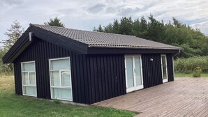 A black building with a tiled roof, large windows, and a wooden deck. - 4 Star Holiday Home in Jerup (Jerup)