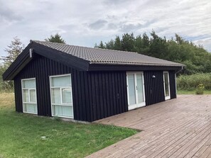 Ein schwarzes Gebäude mit Ziegeldach, großen Fenstern und einer Holterrasse.