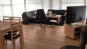 A modern living room with a sofa, chairs, a coffee table, and a television. - 4 Star Holiday Home in Jerup (Jerup)