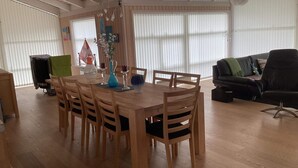 A dining area with a wooden table and chairs, a vase with flowers, and a black sofa in the background. - 4 Star Holiday Home in Jerup (Jerup)