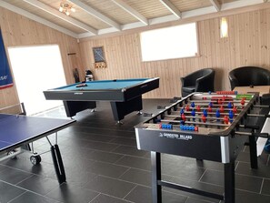 Une salle de billard équipée d’une table de billard, d’un baby-foot et d’une table de ping-pong.