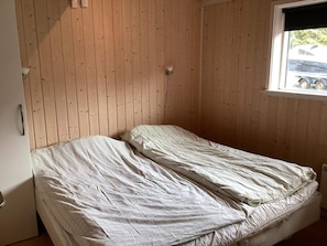 Ein kleines Zimmer mit einem Einzelbett, Holzvertäfelung und einem Fenster.