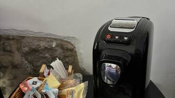 Une machine à café accompagnée d’un panier rempli de diverses collations et d’une petite boîte en bois.
