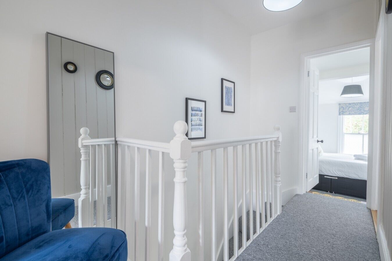 A staircase with white balusters leading to a bedroom with a bed and a window.