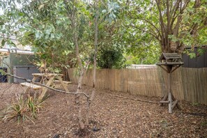 Ein Garten mit Holzzaun, Vogelhaus und Baum.