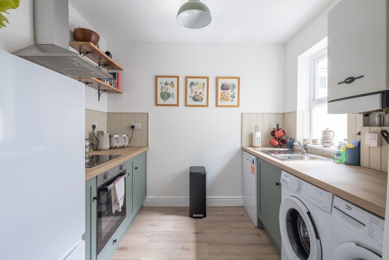 A compact kitchen with a washing machine, a sink, and a small window.