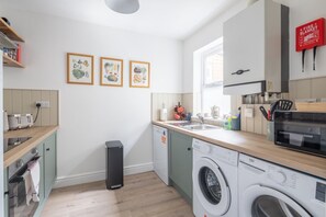 A modern kitchen with a washing machine, a sink, and a fire blanket. - Charming 3Bed Victorian Home PLUS 1 Bed Annexe (Cambridge)