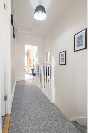 A hallway with a carpeted floor, white walls, and a ceiling light fixture. - Charming 3Bed Victorian Home PLUS 1 Bed Annexe (Cambridge)