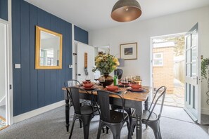 Een eetruimte met een houten tafel voor vier personen, omringd door zwarte stoelen.