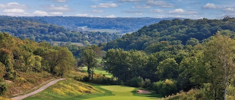 A golf course with a clear view of the surrounding forested hills.