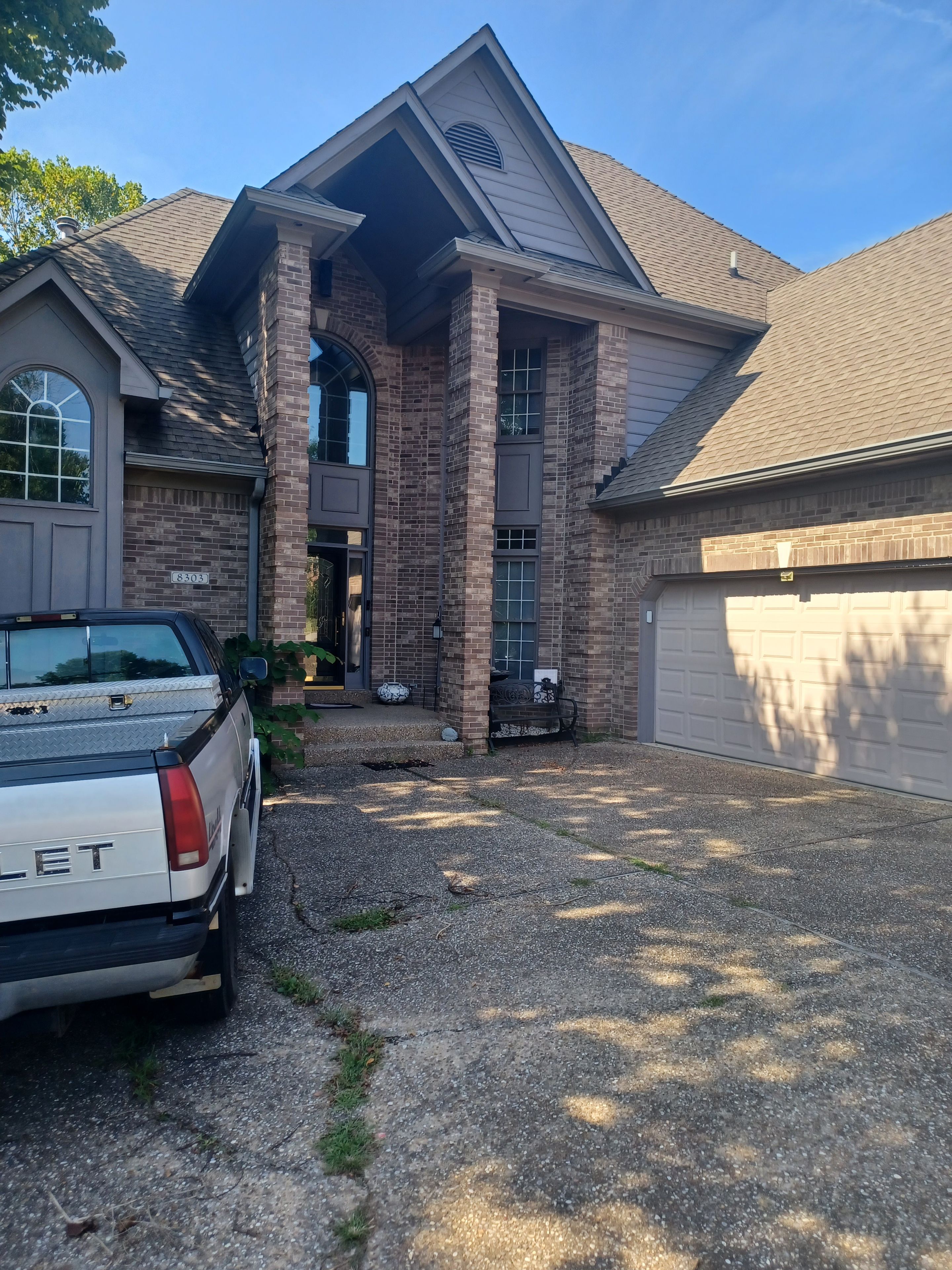 Une maison d’habitation avec un garage, une allée et un camion garé.