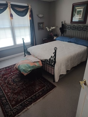 A bedroom with a bed, a nightstand, a mirror, and a window with curtains. - 3-bedroom house in charming Louisville with cool AC breeze (Louisville)