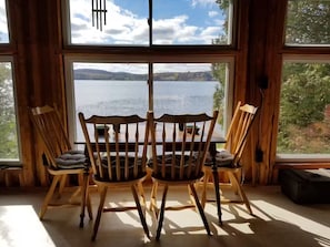 A wooden interior with two chairs facing a large window overlooking a body of water.