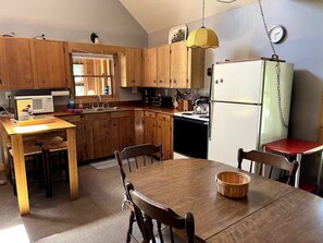 A kitchen with wooden cabinets, a white refrigerator, a stove, and a dining table with chairs.