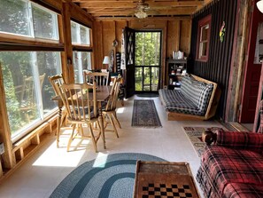 A cozy cabin interior with a dining area, a sofa, and a bookshelf.
