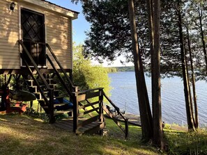 Uma cabana com um píer que se estende por um lago, cercada por árvores.