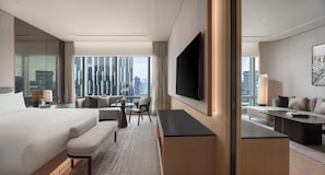 Una habitación de hotel moderna con una cama grande, un escritorio, un televisor de pantalla plana y vistas a la ciudad.