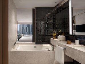 Un baño moderno con una bañera grande, un tocador con espejo y vistas a la ciudad.