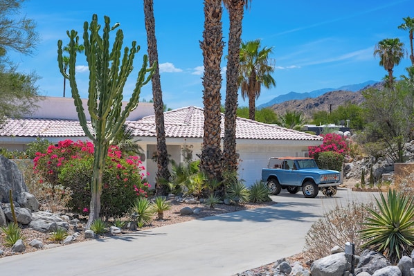 A residential property with a blue pickup truck parked in front, surrounded by desert vegetation and a mountain backdrop. - The Lookout Palm Springs | Stunning Views (Palm Springs)