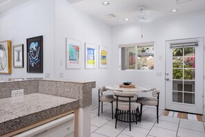 A modern kitchen with granite countertops, a dining area with a marble table, and artwork on the walls. - The Lookout Palm Springs | Stunning Views (Palm Springs)