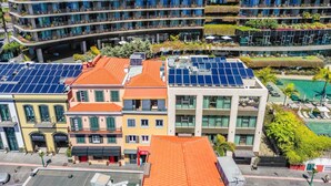 Een meerhoog gebouw met balkons, zonnepanelen en een zwembad.