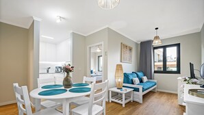 Een moderne woonkamer met een bank, een eettafel met stoelen en een keuken op de achtergrond.