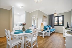 A modern living room with a sofa, a dining table with chairs, and a kitchen area in the background. - Imperatriz 2D by Homie (Funchal)