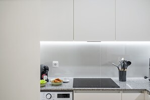 A kitchen with a built-in induction cooktop, a coffee machine, and a bowl of croissants on the counter. - Imperatriz 2D by Homie (Funchal)