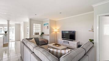 A modern living room with a grey sectional sofa, a coffee table, a TV on a white cabinet, and a floor lamp.
