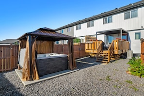 A covered outdoor sleeping area with a wooden bench and a hot tub.