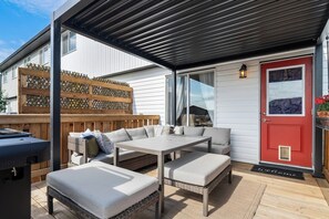 An outdoor patio with a dining table, cushioned seating, and a grill. - Red Door Retreat | Lake | Hot Tub | Fire Pit | AC (Sylvan Lake)