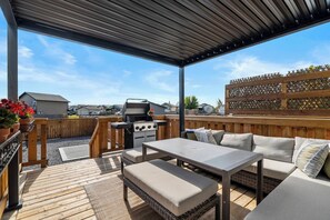 An outdoor patio with a grill, seating area, and a view of the neighborhood.