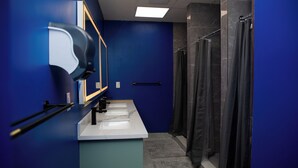 A bathroom with a blue wall, a white sink, a mirror, and a shower curtain.