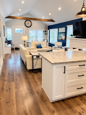 A modern kitchen with white cabinetry, a granite countertop, and a built-in island. - Crystal Beach Long Term Coastal Cottage (Fort Erie)