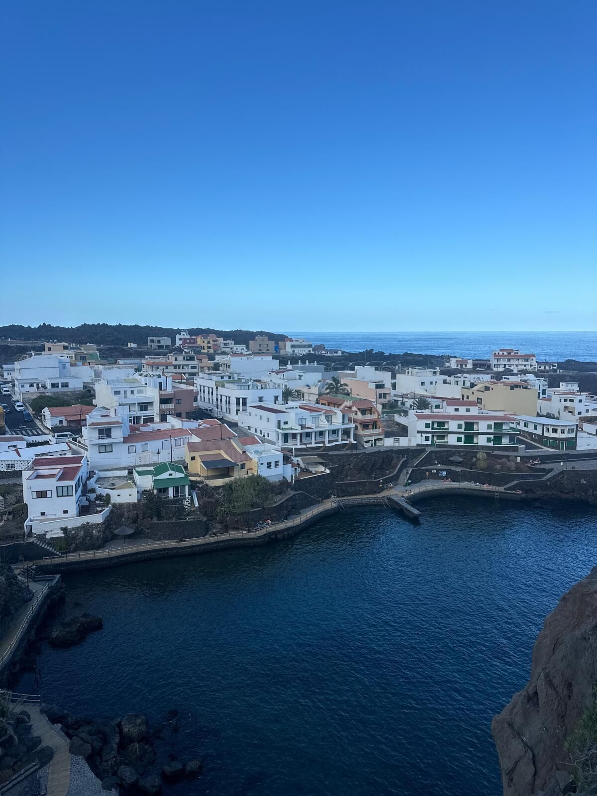 A coastal town with buildings along the waterfront, a clear sky, and a calm sea.