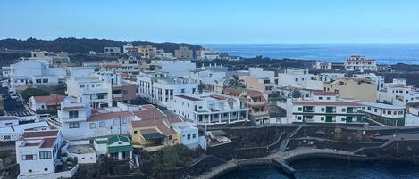 A coastal town with buildings along the waterfront, a clear sky, and a calm sea.