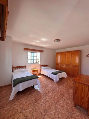 Ein Zimmer mit zwei Betten, einem Holzschrank und einem Fenster.