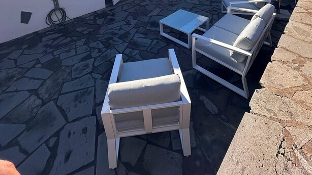 A patio area with stone flooring, white furniture, and a clear blue sky. - El Rinconcito Home in Tamaduste 5 Min from Beach (Tamaduste)