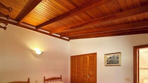 A bedroom with two single beds, wooden ceiling beams, a wall-mounted light, a wooden wardrobe, and a framed picture. - El Rinconcito Home in Tamaduste 5 Min from Beach (Tamaduste)