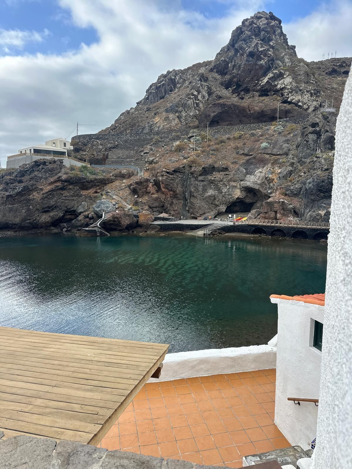 A coastal view with a rocky mountain, a bridge, and a body of water.