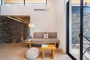 A modern interior with a stone wall, a sofa with cushions, a lamp, and a small table. - Exclusive 4-Villa Beach Estate 11 BR • Sleeps 22 (Pinilla)