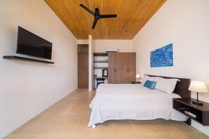 Ein modernes Schlafzimmer mit Bett, Nachttischen, einem Fernseher, einem Deckenventilator und einem Gemälde.