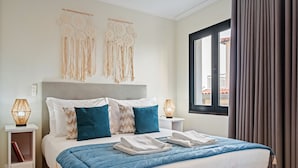 Een hotelkamer met een bed, nachtkastjes, een raam met gordijnen en decoratie aan de muur.