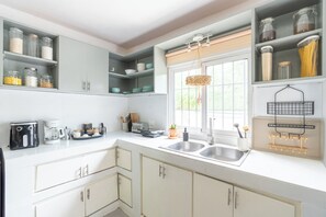 A kitchen with white cabinets, a double sink, and various kitchen appliances. - Apartment with Private Garden and BBQ Area (La Romana)
