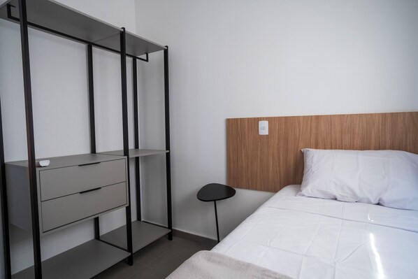 A bedroom with a bed, a wooden headboard, a bedside table, and a wardrobe with a mirror. - Vista Cecap (Guarulhos)