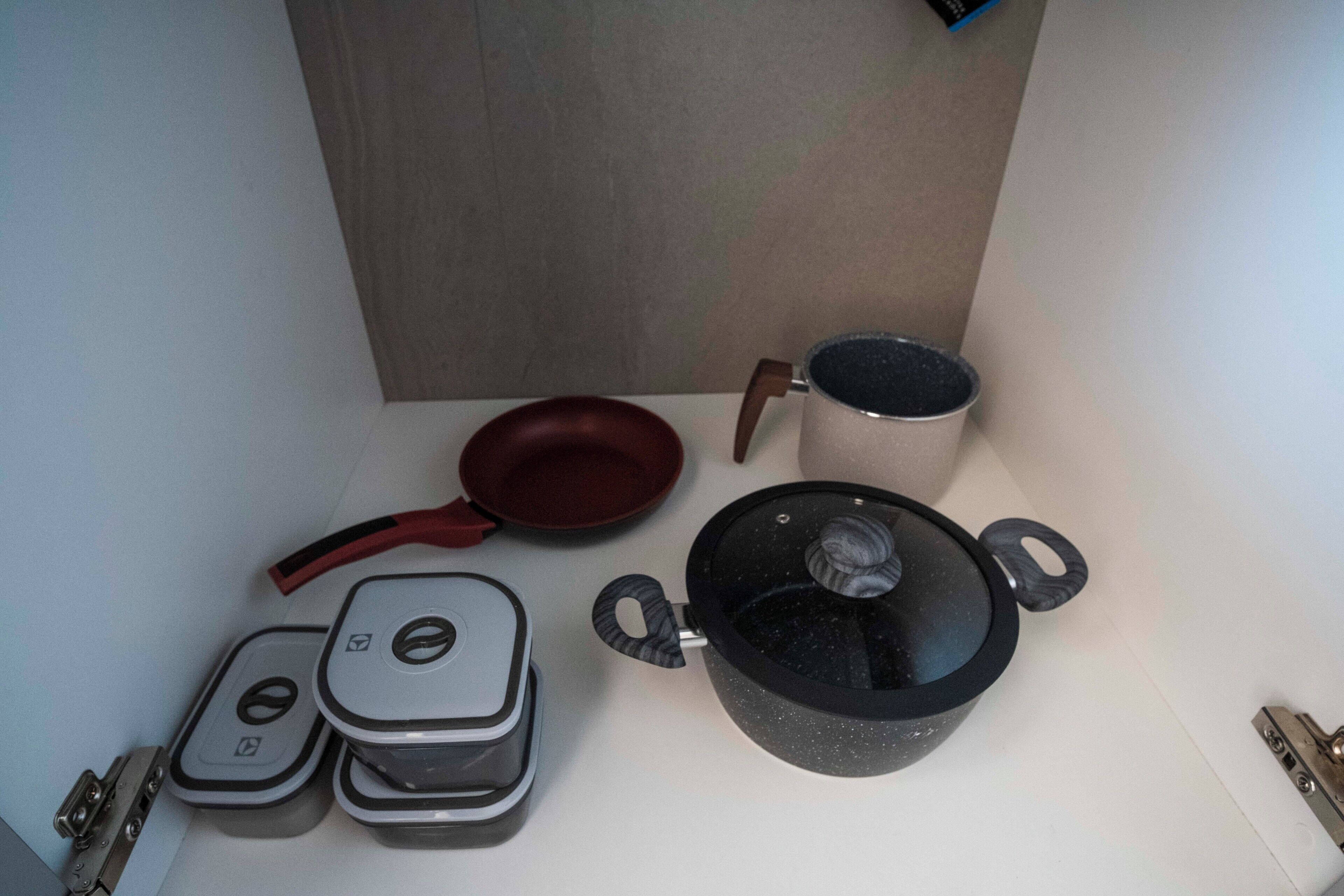 Una cocina con estufa, sartén, olla y tetera.