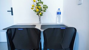 Un salón de conferencias con dos sillas, una botella de agua y un jarrón con flores amarillas.